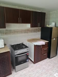a kitchen with a stove and a refrigerator at الخوض السادسة واحة المعرفة in Al Khawḑ