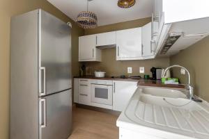 La cuisine est équipée de placards blancs et d'un réfrigérateur en acier inoxydable. dans l'établissement Villa Marcelline - Lyon, à Sainte-Foy-lès-Lyon