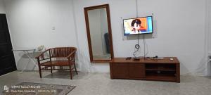 uma sala de estar com uma televisão e uma cadeira em Sobey Laris Homestay TENDONG em Pasir Mas