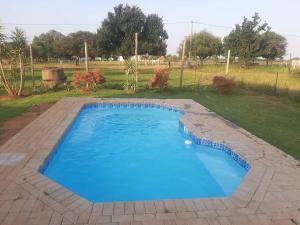 a blue swimming pool in a yard with a field at Umbuntu guesthouse in Parys