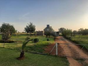 a house on a dirt road with a palm tree at Umbuntu guesthouse in Parys