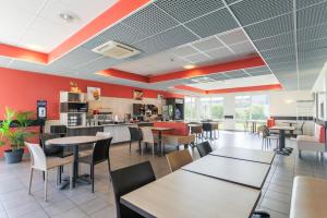 ein Restaurant mit Tischen, Stühlen und roten Wänden in der Unterkunft Ace Hotel Creutzwald Saint Avold in Creutzwald-la-Croix