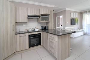 una cucina con armadi in legno e piano di lavoro nero di New Apartment a Chartwell