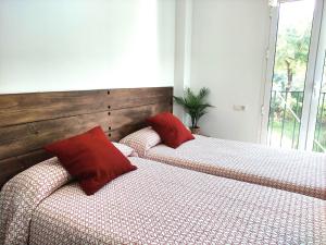 2 Betten mit roten Kissen im Schlafzimmer in der Unterkunft CASA EL SUEÑO DE ARACENA in Aracena