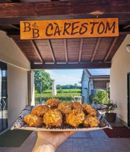 雷焦艾米利亞的住宿－B&B Ca' Restom，持有一盘带有读出冒险的标志的食物的人