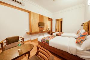 a bedroom with two beds and a table and a television at FabHotel Royale Basant Residency in Bangalore