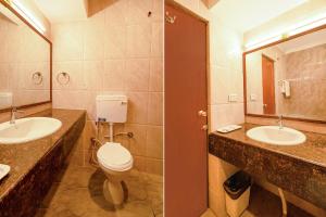 a bathroom with two sinks and a toilet and a mirror at FabHotel Royale Basant Residency in Bangalore