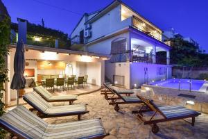 a house with lounge chairs and a swimming pool at Villa Maestral with pool Ciovo in Trogir