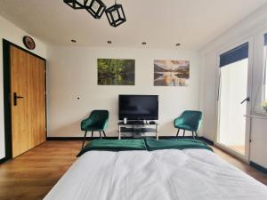 a bedroom with a bed and two green chairs at Na Szczycie in Chełm