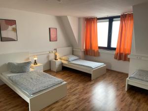 ATRIUM - gemütliche Wohnung RHEINHORST LINKS في لودفيغسهافن أم راين: غرفة نوم بسريرين ونافذة ذات ستائر برتقالية