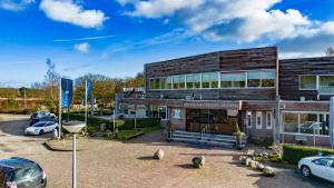 un edificio con coches estacionados en un estacionamiento en Fletcher Hotel - Restaurant de Zeegser Duinen en Zeegse