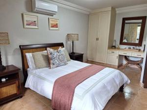 a bedroom with a large bed and a desk at Private Garden Room in Zimbali Estate in Ballito
