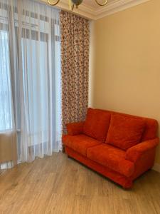an orange couch in a living room with a window at Жк Riverside in Almaty