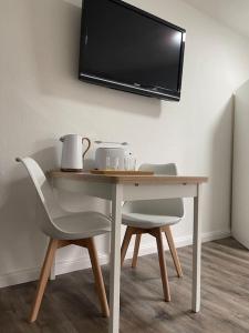 een tafel met twee stoelen en een televisie aan de muur bij 1 Zimmer Appartement in Bad Rothenfelde in Bad Rothenfelde