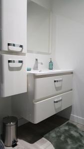 La salle de bains blanche est pourvue d'un lavabo et d'un miroir. dans l'établissement Aux Docks Rémois, à Bétheny