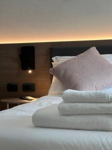 einen Haufen Handtücher auf einem Bett mit Kissen in der Unterkunft Green House in Bassano del Grappa