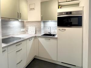 eine Küche mit weißen Schränken und einem Waschbecken in der Unterkunft Apartment Heller am Hasselkopf in Braunlage
