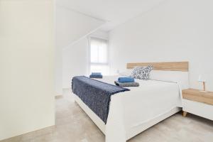 a white bedroom with a large white bed with blue pillows at Apartament Porto Marina in Torre de la Horadada +25 photos