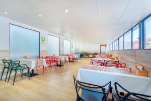 un restaurante con mesas blancas y sillas rojas en 柏高酒店顺德北滘文化公园店 Paco Hotel Shunde Beijiao Midea Group Headquarters store, en Shunde