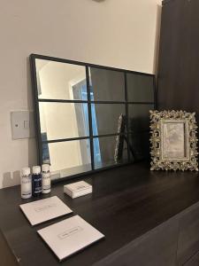 einen Schreibtisch mit einem Spiegel und einem Bild darauf in der Unterkunft Spacious Studio Flat in London in London