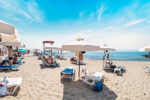 a beach with people sitting on chairs and umbrellas at Privilege Fort Beach Apartments in Sveti Vlas