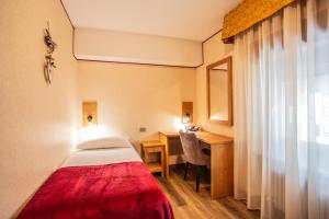 a hotel room with a bed and a desk and a window at Hotel Bijou in Valtournenche