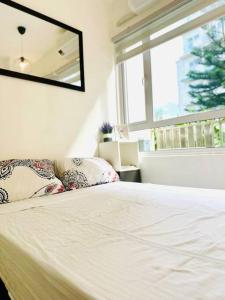 a white bed with pillows in a room with a window at Cool and Savvy 1BR @Cool Suites Tagaytay in Tagaytay