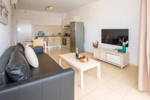 een woonkamer met een zwarte bank en een keuken bij Apartment Austin - Coralli Beachfront Resort in Protaras