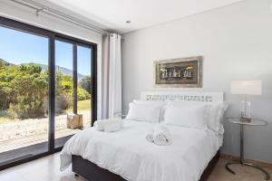 a bedroom with a white bed with a large window at Hangklip Villa by Host Agents in Pringle Bay