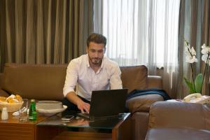 um homem sentado num sofá usando um laptop em Crowne Plaza Amman, an IHG Hotel em Amã