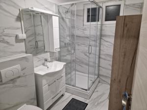 a white bathroom with a shower and a sink at Sobe kuća za odmor apartmani Auto Klarić in Nova Gradiška