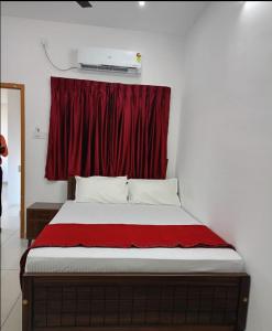 a bed in a room with a red curtain at Sky Residency Lodge in Trichūr