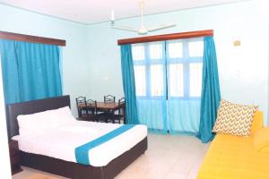 Schlafzimmer mit einem Bett, blauen Vorhängen und einem Tisch in der Unterkunft Swahili House Mweru villa in Mombasa