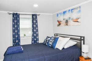 Guest House In The Heart Of Watkins Glen في واتكينز غلين: غرفة نوم مع سرير ووسائد زرقاء وبيضاء