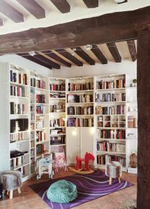 eine Bibliothek mit weißen Bücherregalen mit Büchern in der Unterkunft Domaine de Tardais, Gîte familial avec piscine billard, baby-foot en bordure de forêt in Senonches