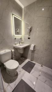 La salle de bains blanche est pourvue de toilettes et d'un lavabo. dans l'établissement Helio Cairo Hotel, au Caire