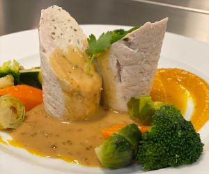 um prato de alimentos com carne e legumes com molho em Hôtel du Commerce-restaurant au Couteau em Nogent