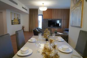 Madinat Jumeirah Living في دبي: طاولة غرفة الطعام مع الأطباق وكؤوس النبيذ