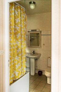 uma casa de banho com uma cortina de chuveiro amarela e um lavatório. em Ma Gentilhommière em Croutoy