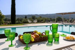 einen Tisch mit einem Obstkorb und Gläsern neben einem Pool in der Unterkunft PODERI LA ROCCHETTA Luxury Villa on the Hills of Lake Garda in San Felice del Benaco