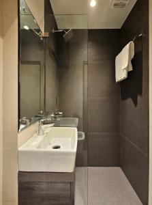 a bathroom with a white sink and a shower at Hotel Kumkum in Mumbai