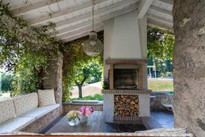 eine Terrasse mit einem Sofa und einem Kamin in der Unterkunft PODERI LA ROCCHETTA Luxury Villa on the Hills of Lake Garda in San Felice del Benaco