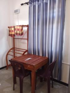 una mesa de madera y una silla junto a una cortina en Villa Don Williams Weligama en Weligama
