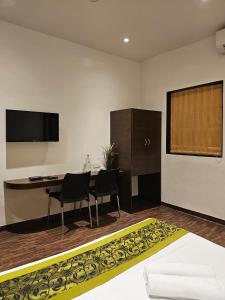 a room with a table and chairs and a television at Hotel Kumkum in Mumbai