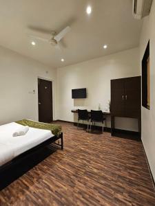 - une chambre avec un lit et un bureau avec des chaises dans l'établissement Hotel Kumkum, à Mumbai