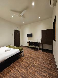 a bedroom with a bed and a desk with chairs at Hotel Kumkum in Mumbai
