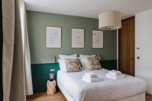 a bedroom with a white bed with a green wall at Maison Hubert B&B in Bordeaux