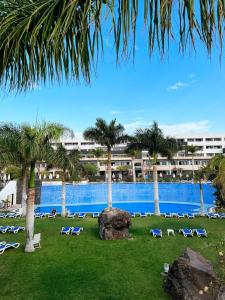 un complexe avec une grande piscine entourée de chaises et de palmiers dans l'établissement Hotel Costa Calero Thalasso & Spa, à Puerto Calero