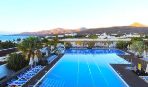 an overhead view of a large swimming pool with chairs and the ocean at Hotel Costa Calero Thalasso & Spa in Puerto Calero