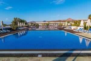 een zwembad met stoelen en parasols in een resort bij Hotel Costa Calero Thalasso & Spa in Puerto Calero